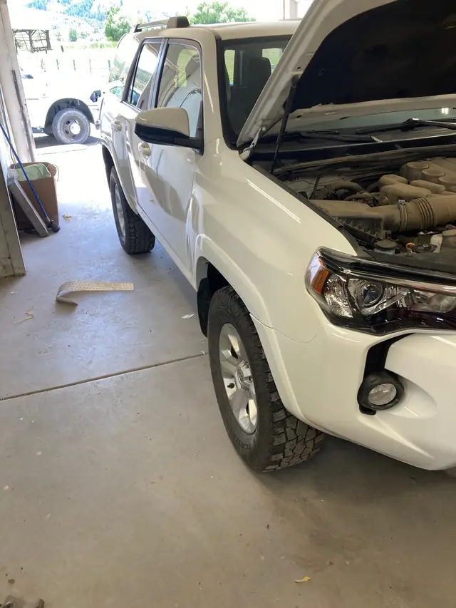 White Toyota 4Runner in the shop with the hood up during front-end repair