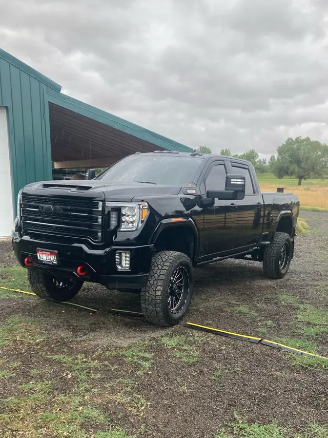 Black lifted GMC Sierra parked by the barn after finishing